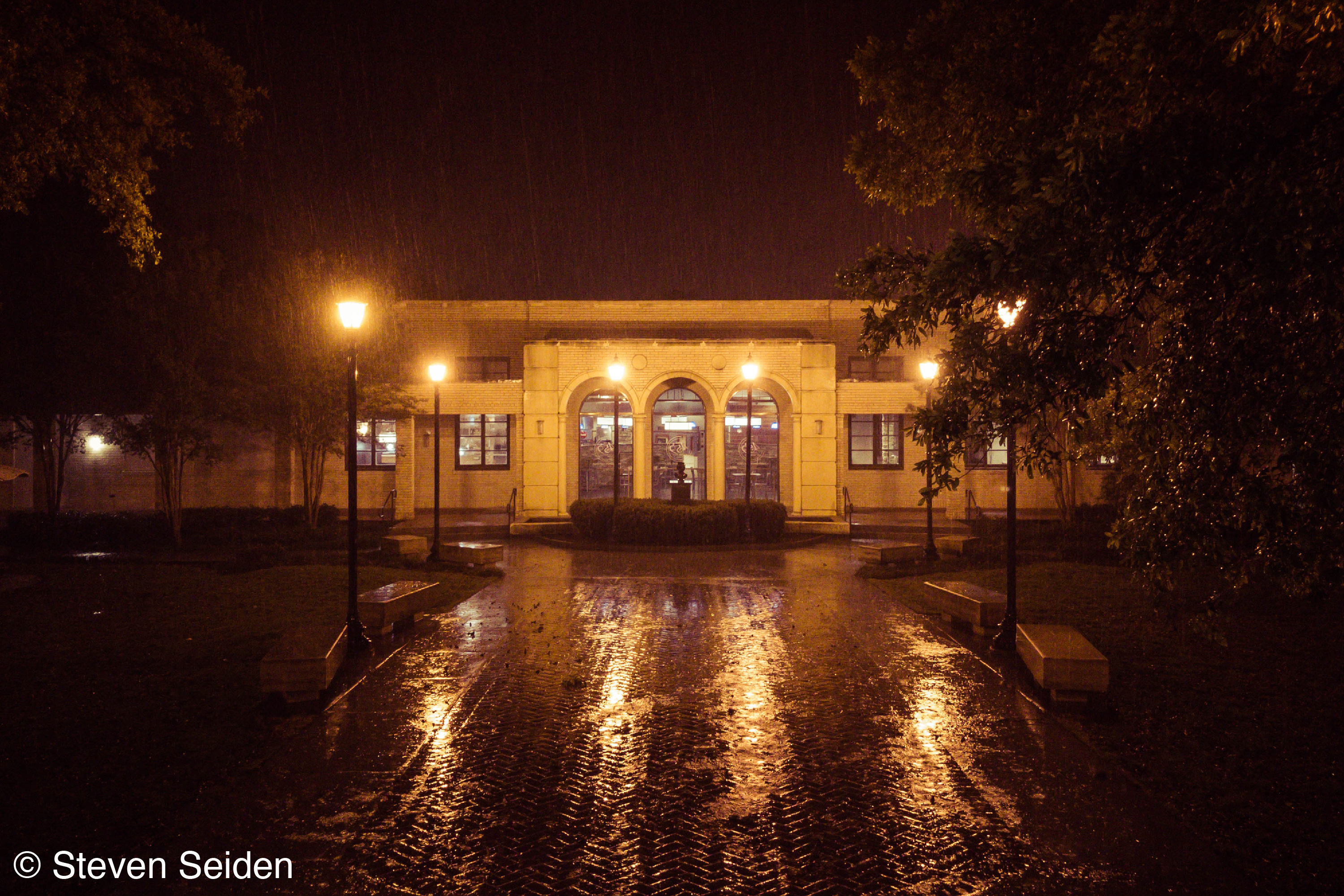 A picture of a building taken in the rain at night.